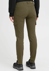 Pantaloni cargo verde oliva con una vestibilità slim, dotati di due tasche laterali e una finitura testurizzata. Progettati con cuciture sottili e una fascia con marchio.