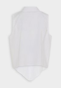Camisetta senza maniche bianca con un orlo posteriore a punta, dotata di colletto e tessuto texturizzato. Design pulito e minimal senza ulteriori decorazioni.
