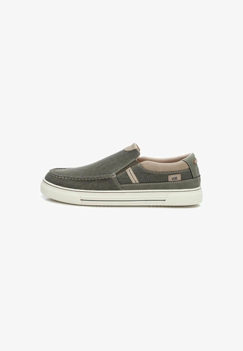 Zapatos tipo slip-on en tela verde oscuro con acentos beige, presentando una superficie texturizada, suela de goma blanca y detalles de costura mínimos.