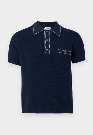 Polo in maglia blu navy a maniche corte con cuciture bianche a contrasto su colletto, pattina dei bottoni e taschino sul petto con bottone emblema dorato.