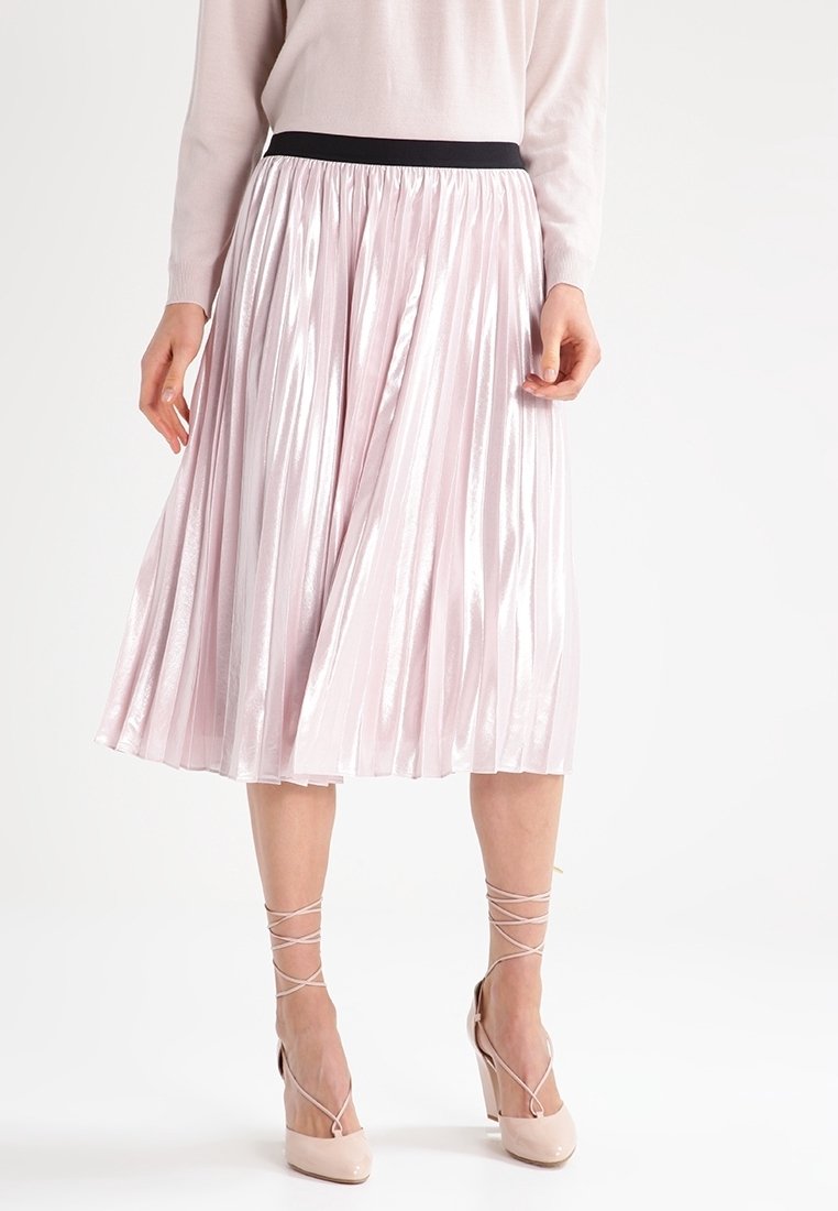 Rosa plisserad midikjol med svart elastisk midjeband, med en glänsande textur och mjukt fall, kombinerad med ljusa högklackade skor.