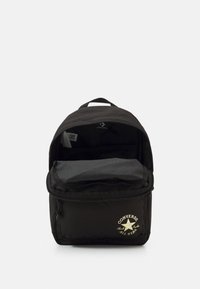 Sac à dos noir avec une poche zippée à l'avant, des bretelles rembourrées et un logo. L'intérieur comprend un grand compartiment et un revêtement doux et texturé.