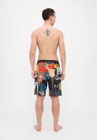 Värikasset simshorts med en livlig design med djurmotiv och grafiska element på en svart bakgrund, elastisk midja och avslappnad passform.
