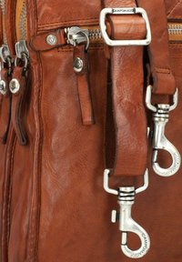 Bruine leren tas met een gestructureerd oppervlak, zilveren metalen hardware, meerdere rits sluitingen en verstelbare straps met clipsluiting.