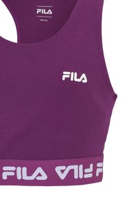 Lila atletisk crop top gjord av mjukt tyg, med en vit logotyp på framsidan och ett kontrasterande vitt band med logotyp längst ner.