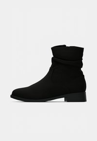 Mustad mustad saapad, mis on valmistatud pehmest siga nahast, laia disainiga, ümarate varvastega ja madala plokkninaga. Minimalistlik stiil, millel ei ole nähtavat riistvara.