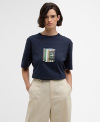 T-shirt de algodão azul marinho com um design de bolso redondo e listrado colorido, apresentando uma ilustração de lata. Combinado com calças largas bejes.
