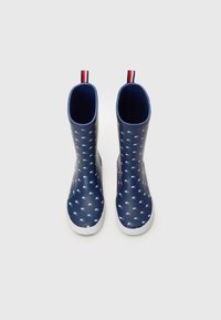 Bottes de pluie en caoutchouc navy avec un motif à motifs carrés répétés en bleu et rouge. Semelle blanche, design robuste et languette de tirage en haut pour un enfilage facile.