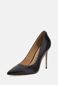 Scarpa con tacco alto in pelle nera, punta appuntita, superficie liscia e tacco a stiletto sottile. L'interno è beige con l'etichetta del marchio visibile.