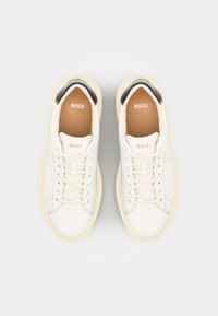 Witte leren sneakers met een ronde neus, veters, gele rubberen zool en een zwarte accent bij de hiel. Het "BOSS"-logo staat op de tongen.