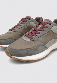 Sneaker grigie e taupe con un mix di suede e tessuto, dotate di lacci bordeaux, una suola intermedia bianca e una suola esterna in gomma testurizzata color gum.