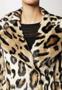 Leopardprint nep-bont jas met een brede kraag, dubbelknopensluiting en een zachte, textuurachtige oppervlakte in tonen van bruin en zwart.