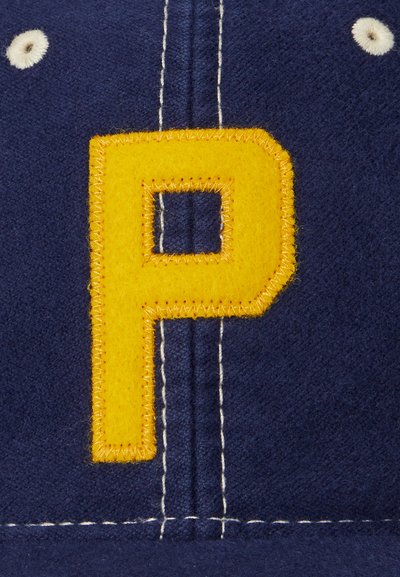 Caciula de marine cu o broderie mare galbenă în formă de literă "P", contrastată de cusături albe și un accent format din două puncte albe.