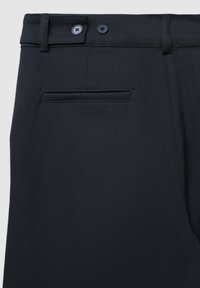 Schwarze Hose mit glatter Textur, ausgestattet mit einem knöpfbaren Bund und einer Gesäßtasche. Der Stoff wirkt langlebig und knitterfrei.