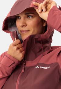 Giacca da donna di colore rosa scuro, con chiusura a zip, cappuccio regolabile e tessuto texturizzato. Logo sul petto, con un rivestimento interno a contrasto.