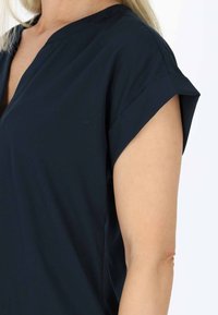 Kurze ärmellose Bluse in Marineblau mit V-Ausschnitt, aus glattem Stoff gefertigt. Mit umgeschlagenen Ärmeln und einer entspannten Passform.