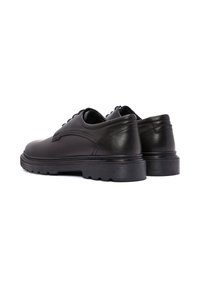 Chaussures en cuir noir à bout rond, avec des lacets plats et une semelle en caoutchouc texturée. Présentent des accents de couture et un design élégant.