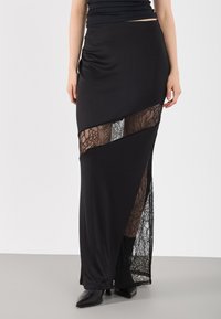 Μαύρη μάξι φούστα με ένθετα από δαντέλα, με πλαϊνή σχισμή και λεπτό ύφασμα. Σχεδιασμένη για εφαρμοστή σιλουέτα, συνδυασμένη με μαύρα μποτάκια αστραγάλου.