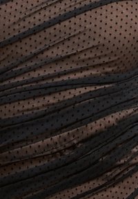 Tessuto in rete nera a pois con texture arricciata, caratterizzato da pieghe sovrapposte e piccoli pois distribuiti uniformemente. Aspetto leggero e trasparente.
