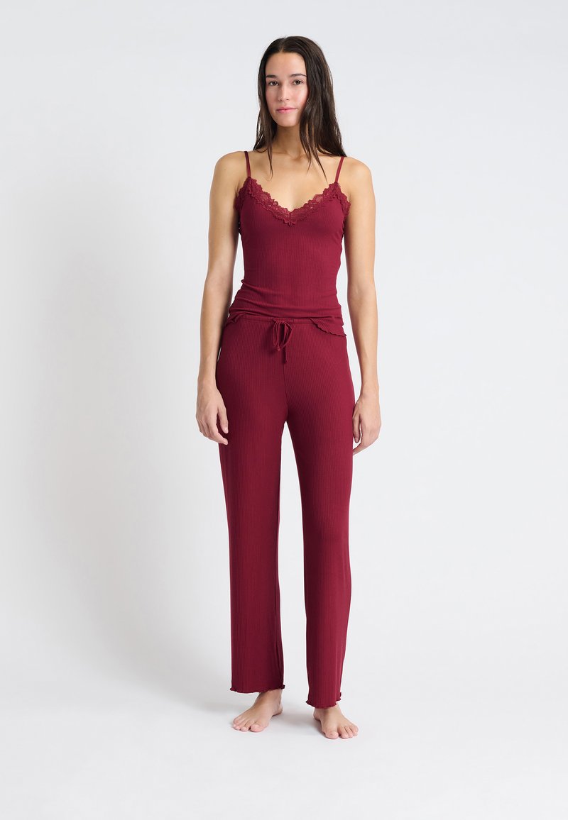 Bordeaux-randig lounge-set som innehåller en ärmlös topp med spetskant och matchande byxor med dragsko och fransad fåll. Mjuk textur.