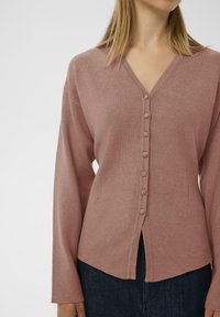 Rosenfarbenes Cardigan aus weichem Strickstoff, mit V-Ausschnitt, sieben Knöpfen vorne und einem leicht abgerundeten Saum mit Seitenschlitzen.