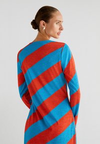 Gestreepte jurk in gedurfde rode en blauwe kleuren, met lange mouwen, een ronde halslijn en een losse pasvorm met een glanzende textuur.