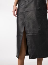 Zwarte leren midi-rok met een voorknijp, gestructureerde stiksels en een zachte textuur. Het ontwerp toont verticale panelen.