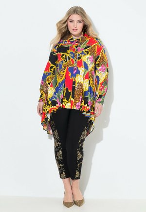 Kleurige blouse met patroon en een high-low zoom, met bloemen- en luipaardmotieven. Gecombineerd met zwarte legging versierd met gouden bloemaccenten.