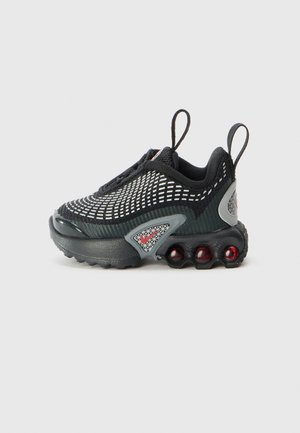 Chaussure de sport noire et grise avec un motif en maille blanche, deux languettes de traction, et une semelle comportant quatre coussins d'air rouges sur un fond uni.