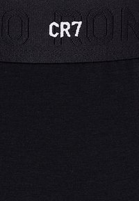 Sort undertøj med en sort elastisk talje, der har en forhøjet "CR7" logo i hvid. Glat tekstur, tætsiddende design, minimal detaljering.