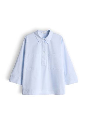 Lichtblauwe blouse met lange mouwen, puntige kraag, drieknoopssluiting en twee borstzakken aan de voorkant, plat uitgestald op een witte achtergrond.