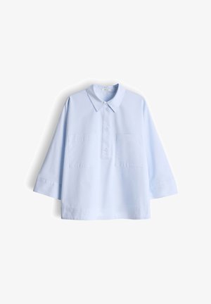 Lichtblauwe blouse met lange mouwen, puntige kraag, drieknoopssluiting en twee borstzakken aan de voorkant, plat uitgestald op een witte achtergrond.