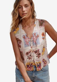 Sleeveless floral patterned top in light fabric with a V-neckline and drawstring detail at the front. Features various botanical designs in pastel colors.