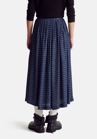 Blue patterned maxi skirt with pleats, made of lightweight fabric. Worn with black ankle boots and white ribbed socks for contrast.