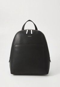 Čierny kožený batoh s guľatým tvarom, strieborným kovaním, predným vreckom a dvojitým zipsovým uzáverom. Má hornú rukoväť na prenášanie.