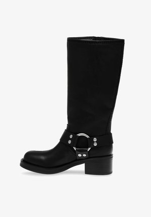 Stivale nero al ginocchio con punta arrotondata, texture in pelle liscia, cerniera laterale e una fascia decorativa con una fibbia circolare argentata.