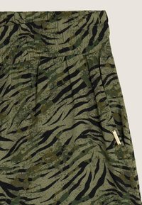 Falda verde con un patrón de rayas de tigre en negro y verde oscuro. Diseño plisado con un detalle de etiqueta dorada en el lateral.