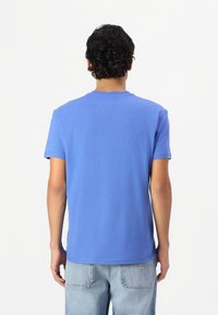 Blå bomulds T-shirt med korte ærmer, rund halsudskæring og en lige kant. Har et enkelt design uden synlige mønstre eller accenter.