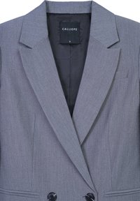 Blazer grigio doppiopetto con rever appuntito, due bottoni neri e tasche laterali. L'interno presenta una fodera nera liscia. Etichetta del marchio visibile.