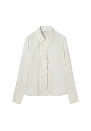 Camicia bianca a maniche lunghe con colletto appuntito e dettaglio asimmetrico di volant lungo la patta dei bottoni frontale.