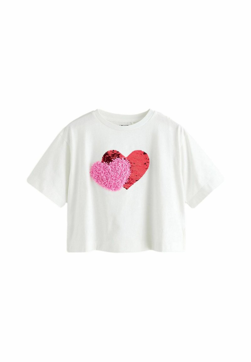 T-shirt court à manches courtes blanc avec deux appliqués en forme de cœur : un en sequins rouges et un en peluche rose. Matière en coton doux, coupe décontractée.
