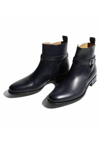 Botas de tobillo de cuero azul marino con un diseño elegante, que presentan una correa con hebilla y una textura suave, además de un tacón bajo para mayor estabilidad.