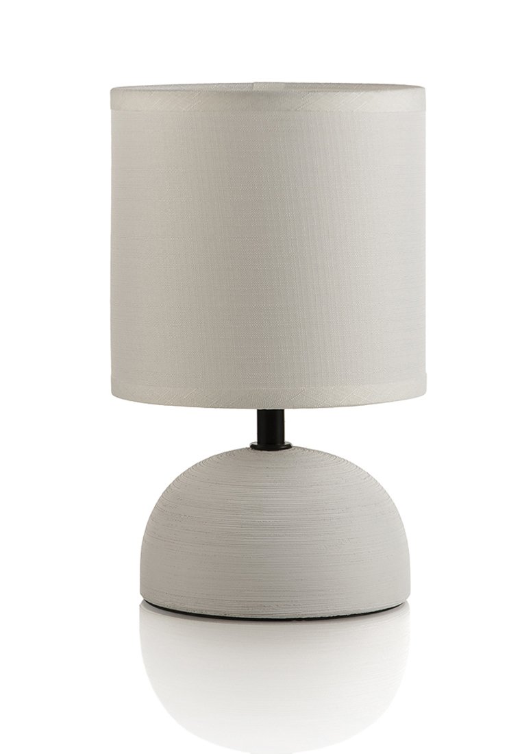 Stolní lampa s kulatou, texturovanou šedou základnou a válcovým textilním stínidlem v světlém neutrálním odstínu, umístěná na černém stojanu.