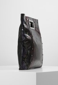 Svart och metallisk ormskinnstote med en slank design, en texturerad yta, och silverdetaljer samt en rektangulär hårdvarudetalj.