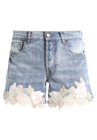 Shorts vaqueros en azul claro con un acabado desgastado. El dobladillo presenta bordado de encaje floral blanco y detalles transparentes a lo largo del borde inferior.