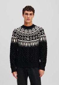 Pull noir avec un motif en tricot torsadé texturé, dot�é d'une encolure à yoke à motif blanc. Poignets et ourlet côtelés.
