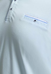 Polo bleu clair avec patte de boutonnage et poche poitrine décorative boutonnée avec bordure bleue et blanche.