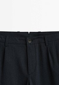 Dunkle, strukturierte Stoffhosen mit einem Bund und schwarzem Knopfverschluss. Vordere Falten verleihen dem Design Struktur.