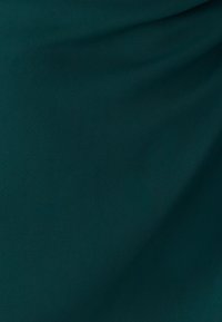 Tessuto verde scuro, testurizzato con superficie liscia. Presenta motivi sottili intrecciati e una leggera lucentezza, adatto per abbigliamento o arredo casa.