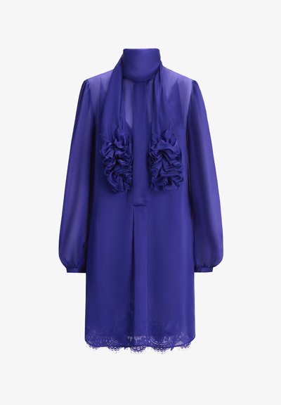 Violet chiffon-mekko, jossa on korkea kaula-aukko, pitkät hihat ja röyhelöitä edessä. Alareunassa on pitsikoriste.